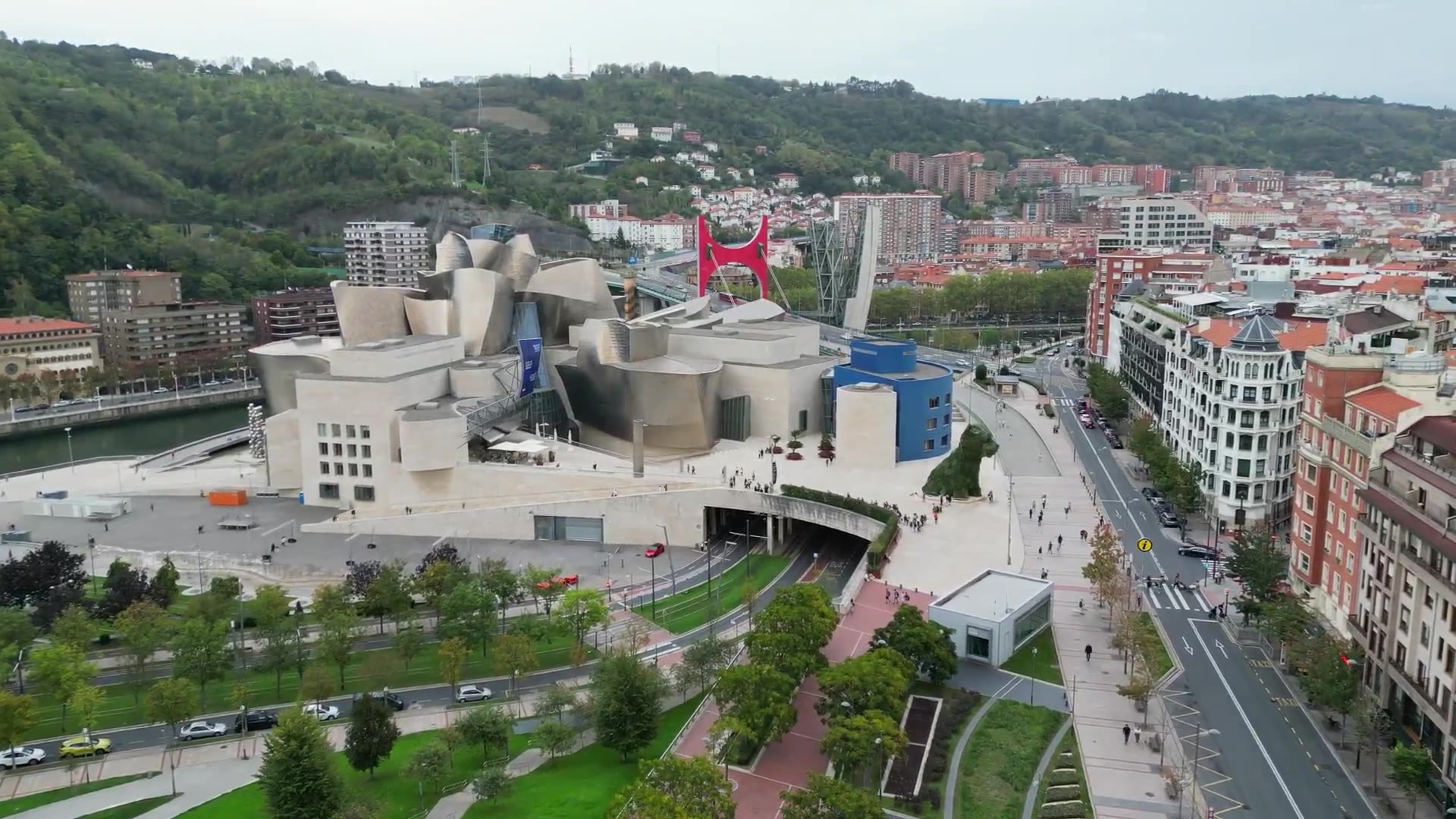 El Museo Guggenheim Bilbao visto desde arriba, con el arco rojo del puente de La Salve detrás